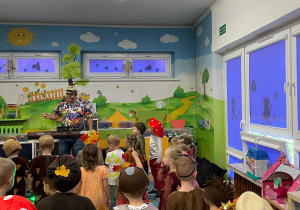 Dzieci bawią się przy muzyce nauczyciela prowadzącego rytmikę.