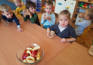 grupa dzieci przy stolikach ze szklankami z sokiem z owoców