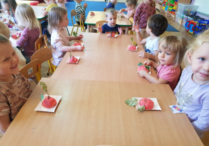 grupa dzieci przy stolikach z ulepionymi jabłuszkami i z gałązką na tacy