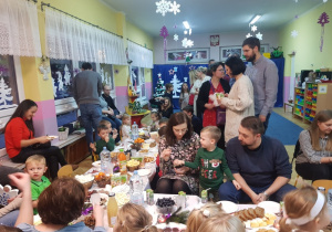 dzieci z rodzicami przy stolikach świątecznie zastawionych