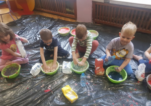 grupa dzieci wyrabiająca masę plastyczną w miskach