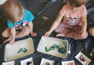 grupa dzieci malująca na tackach z mlekiem i olejem barwnikami spożywczymi