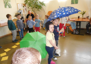 grupa dzieci w storjach zwierząt pod parasolem podczas występu