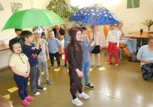 grupa dzieci w storjach zwierząt pod parasolem podczas występu