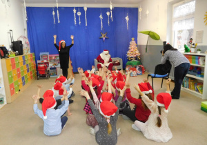 grupa dzieci w czerwonych swiątecznych czapkach podczas występu dla Mikołaja