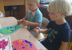 Dzieci przy stole malują farbami