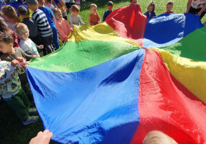 Grupa dzieci trzyma kolorowa chustę animacyjną