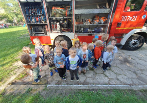 Grupa dzieci stoją przed wozem strażackim