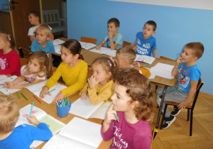 grupa dzieci siedzących przy stolikach podczas zajęć