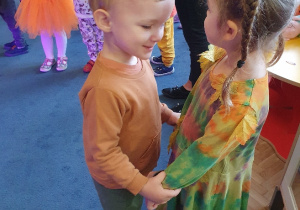 Dwoje dzieci przebrane w stroje jesienne tańczą w parze
