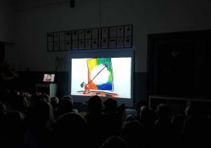 grupa dzieci podczas oglądania filmu edukacyjnego w zaciemnionej sali