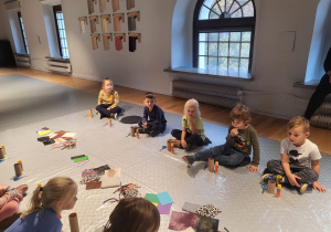 dzieci podczas warsztatów plastycznych w sali na podłodze