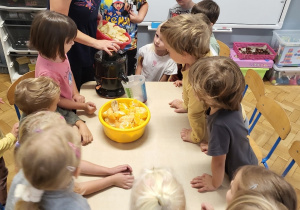 dzieci przy stolikach przygotowują owoce do sokowirówki