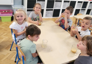 dzieci przy stolikach piją sok ze szklanek