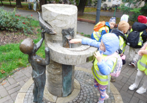 dzieci przy pomniku ze zródełkiem