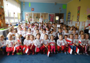 dzieci w strojach biało czerwonych zgromadzone na sali
