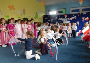 dzieci na tle dekoracji podczas występu ze wstęgami