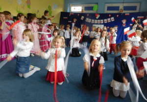 dzieci na tle dekoracji podczas występu ze wstęgami