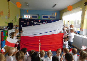 dzieci tworzą flagę z sukna białego i czerwonego