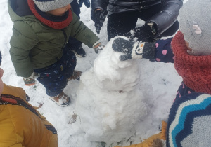 Dzieci na śniegu lepią bałwana