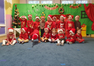 Grupa dzieci ubranych na czerwono w mikołajowych czapkach