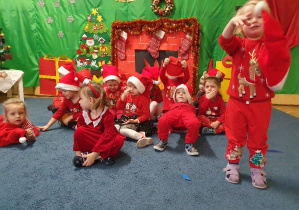 Grupa dzieci ubranych na czerwono w mikołajowych czapkach