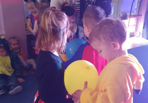 chłopiec i dziewczynka tańczą z balonem pośrodku