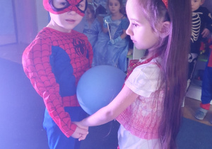 chłopiec i dziewczynka tańczą z balonem pośrodku