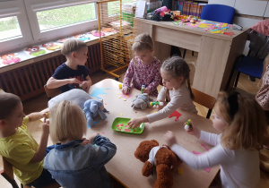 dzieci przy stolikach podczas pracy plastycznej z misiem