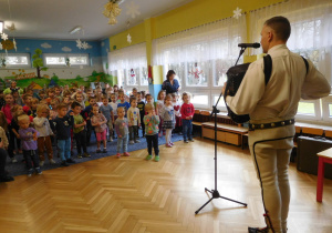 Góral demonstruje dzieciom grę na instrumencie muzycznym