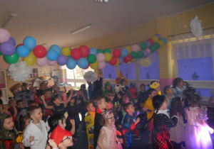 grupa dzieci w strojach karnawałowych w sali udekorowanej balonami