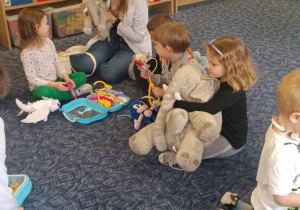Dzieci siedzą na dywanie bawią się zastawem lekarskim