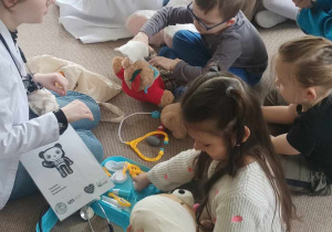 Dzieci siedzą na dywanie bawią się zastawem lekarskim