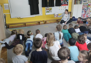 Dzieci słuchają czytanej im bajki.