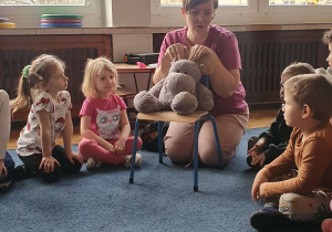 Dzieci siedzą w kole z panią stomatolog prowadzącą zajęcia