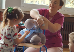 Dzieci siedzą w kole z panią stomatolog prowadzącą zajęcia