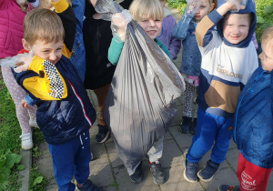 Grupa dzieci trzyma w ręku plastikowy worek na śmieci