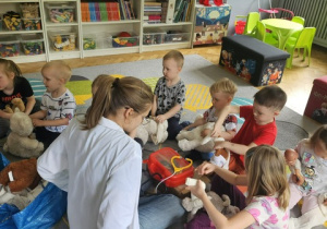 Dzieci siedząc na dywanie badają pluszowe misie