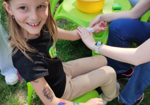 Dziewczynka pozuje do zdjęcia podczas wykonywania tatuażu.