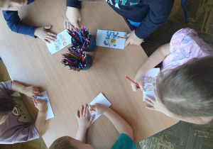 dzieci przy stoliku wykonują prace plastyczną