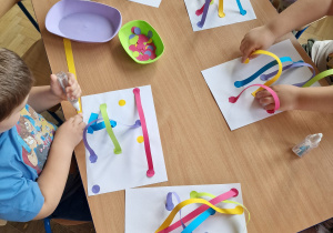 dzieci przy stolikach wykonuja pracę plastyczną