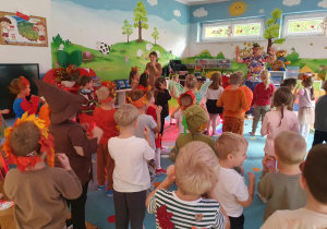 dzieci przebrane w stroje jesienne tańczą w sali przedszkolnej