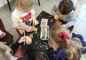 dzieci siedzą przy stoliku wykonują pracę plastyczną