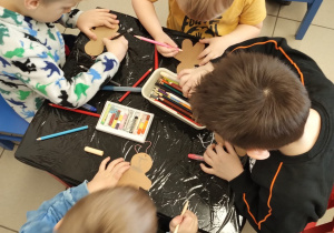 dzieci siedzą przy stoliku wykonują pracę plastyczną