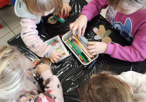 dzieci siedzą przy stoliku wykonują pracę plastyczną