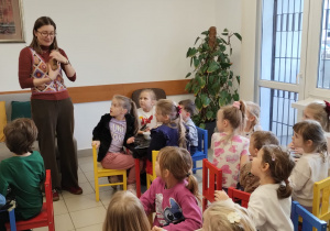 dzieci siedzą przed panią bibliotekarką, która pokazuje wytwory świąteczne