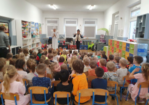 dzieci siedzą na dywanie na występie muzycznym