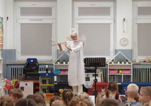 kobieta przebrana za anioła gra na flecie