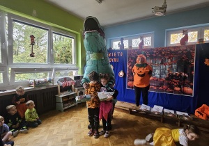 osoba przebrana za dinozaura razem z dziećmi