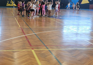 Grupa dzieci przybija piątki z nauczycielem.